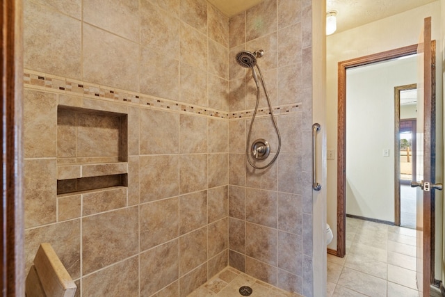 bathroom featuring a tile shower, tile patterned floors, and toilet