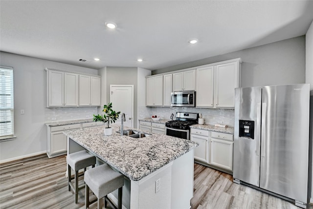 kitchen featuring white cabinets, appliances with stainless steel finishes, sink, and a kitchen island with sink