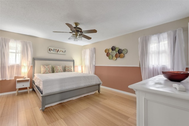 bedroom featuring hardwood / wood-style flooring, ceiling fan, and a textured ceiling