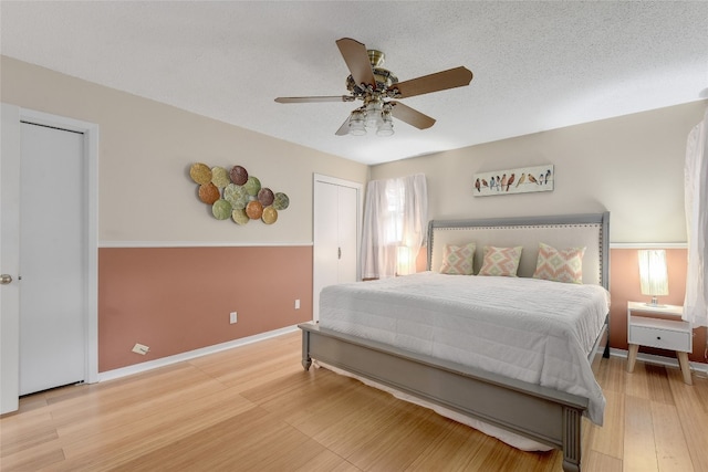 bedroom featuring ceiling fan, a textured ceiling, and light wood-type flooring