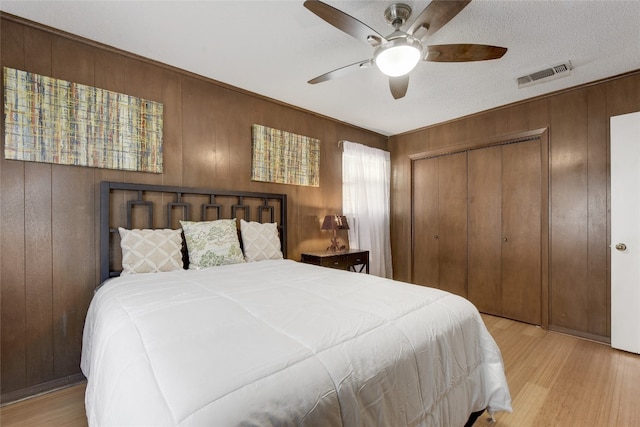 bedroom featuring wooden walls, a closet, and light wood-type flooring