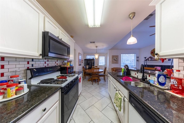 kitchen featuring sink, white cabinetry, hanging light fixtures, decorative backsplash, and gas range