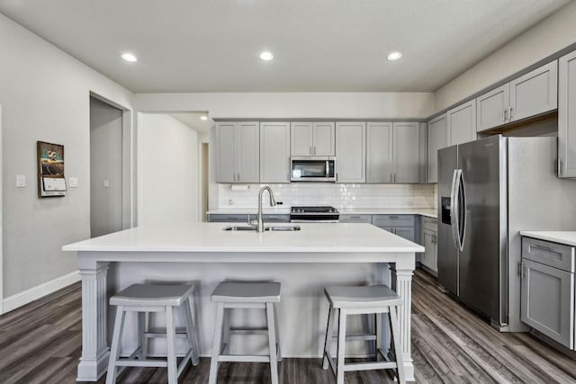 kitchen with sink, gray cabinets, stainless steel appliances, and an island with sink