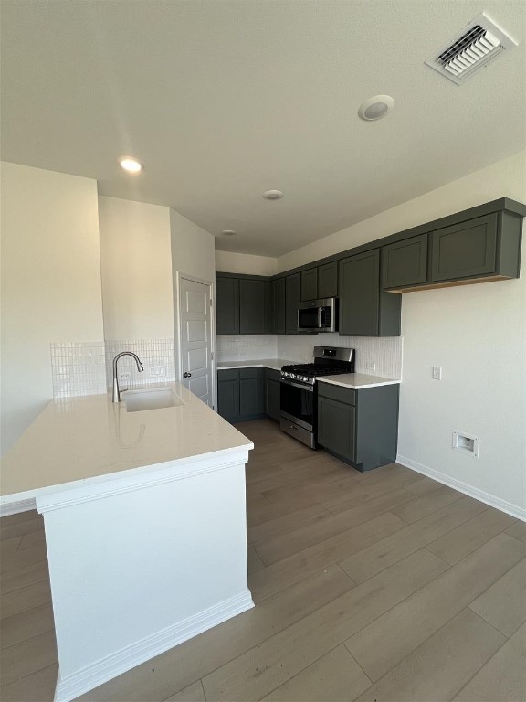 kitchen featuring sink, gray cabinetry, stainless steel appliances, light hardwood / wood-style floors, and kitchen peninsula