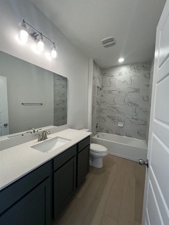 full bathroom with tiled shower / bath combo, vanity, and toilet