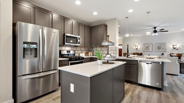 kitchen featuring stainless steel appliances, a center island, sink, and hanging light fixtures