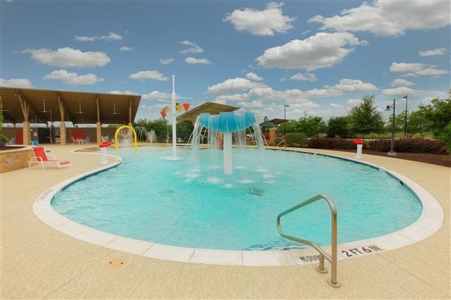 view of swimming pool with pool water feature and a patio area