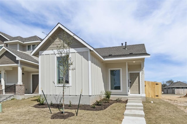 view of front facade with a shingled roof, fence, and board and batten siding