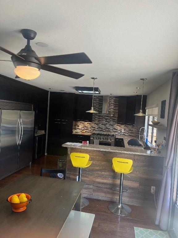 kitchen featuring tasteful backsplash, high end appliances, a kitchen bar, and decorative light fixtures