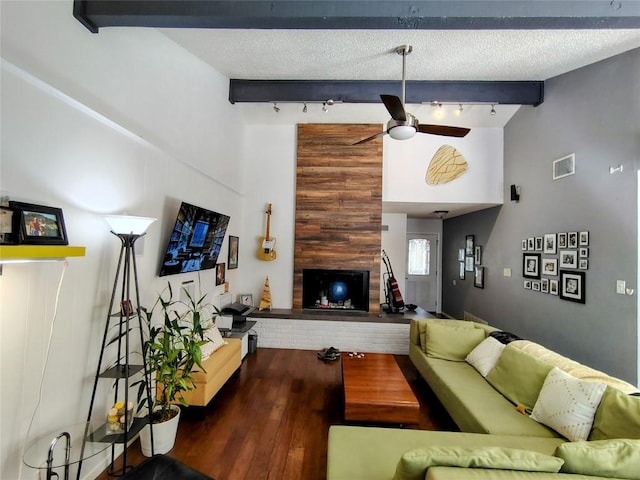 living area with a large fireplace, lofted ceiling with beams, a textured ceiling, and visible vents