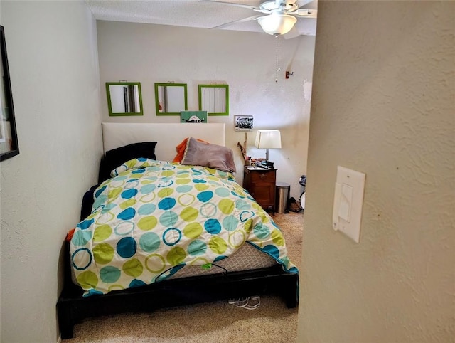 carpeted bedroom with a ceiling fan and a textured wall