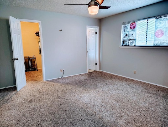 unfurnished bedroom featuring carpet floors, a textured ceiling, baseboards, and a spacious closet