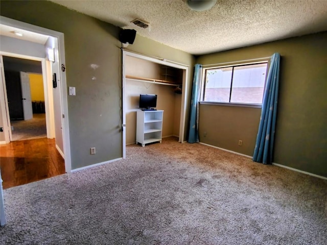 unfurnished bedroom featuring a textured ceiling, a closet, carpet flooring, and visible vents