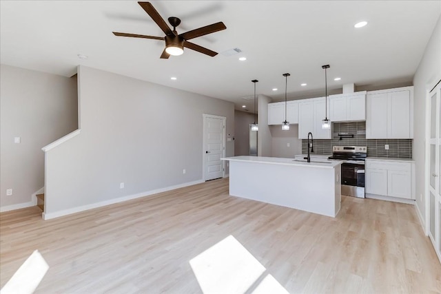 kitchen featuring sink, white cabinetry, decorative light fixtures, an island with sink, and stainless steel electric stove