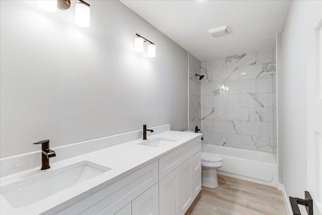 full bathroom with hardwood / wood-style flooring, vanity, toilet, and tiled shower / bath combo