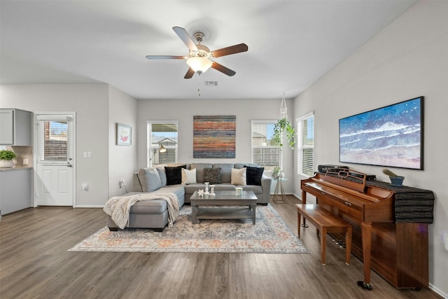 living area featuring visible vents, wood finished floors, a ceiling fan, and baseboards