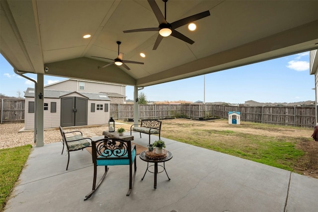 view of patio featuring a ceiling fan, a fenced backyard, an outdoor structure, and a shed