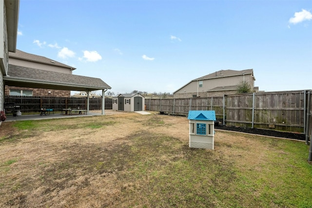 view of yard featuring a storage shed, a patio area, a fenced backyard, and an outbuilding