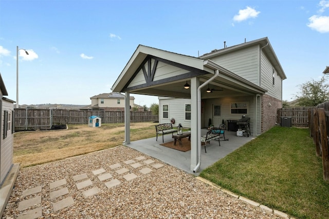 rear view of property with ceiling fan, a patio, a fenced backyard, brick siding, and a yard