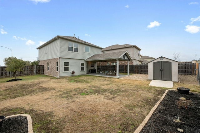 back of property with a storage shed, a lawn, a patio, a fenced backyard, and an outbuilding