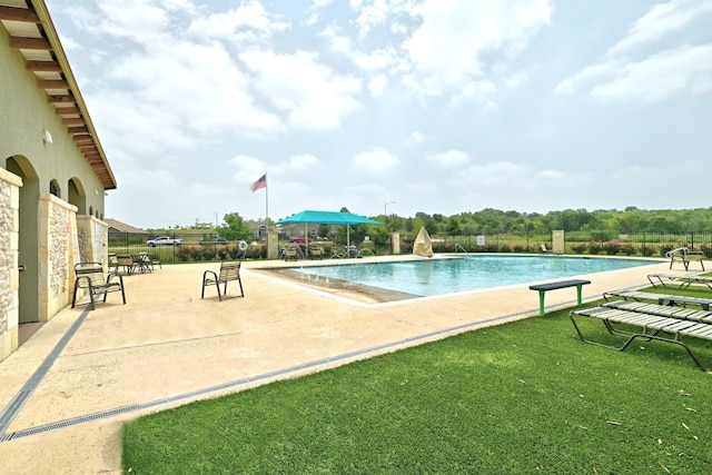 pool with a patio, a yard, and fence