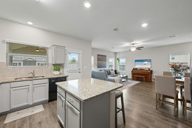 kitchen featuring dark wood-type flooring, a kitchen island, visible vents, dishwasher, and tasteful backsplash