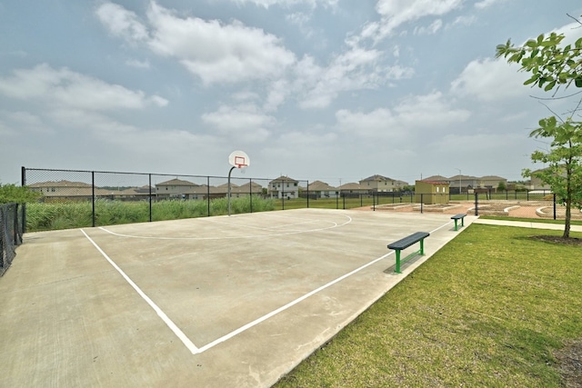 view of basketball court featuring community basketball court, a lawn, fence, and a residential view