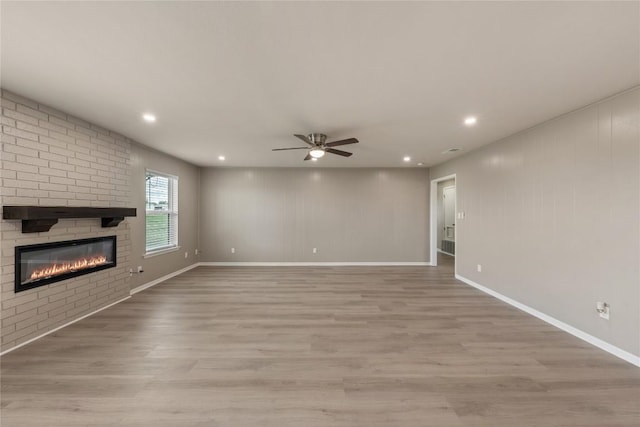 unfurnished living room featuring ceiling fan, a fireplace, and light hardwood / wood-style flooring