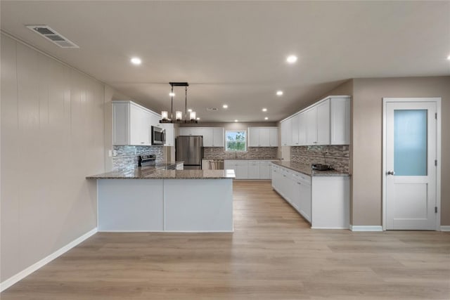 kitchen with white cabinetry, hanging light fixtures, stainless steel appliances, and kitchen peninsula