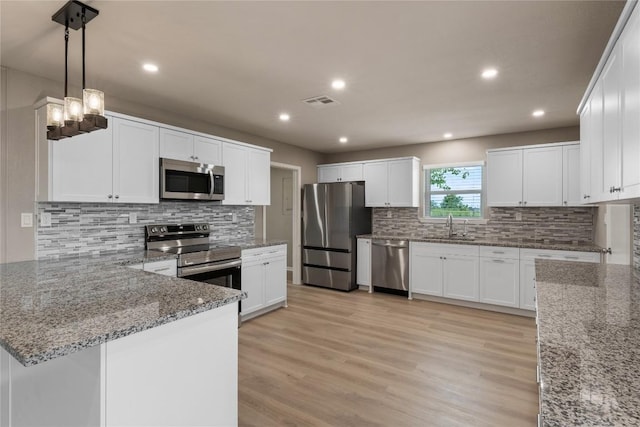 kitchen with light hardwood / wood-style flooring, stainless steel appliances, white cabinets, and stone countertops