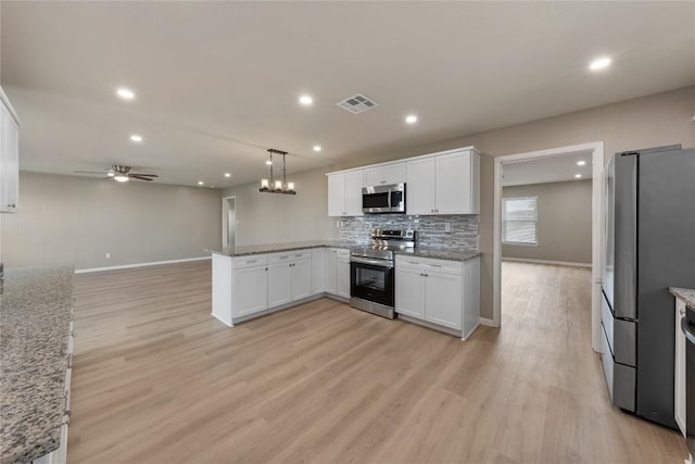 kitchen with hanging light fixtures, kitchen peninsula, stainless steel appliances, decorative backsplash, and white cabinets