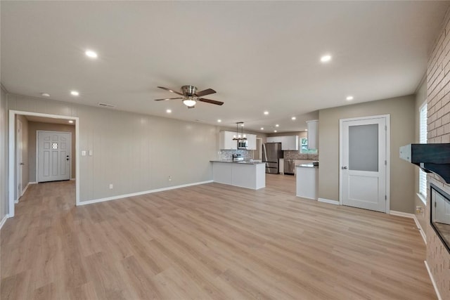 unfurnished living room featuring ceiling fan and light hardwood / wood-style floors