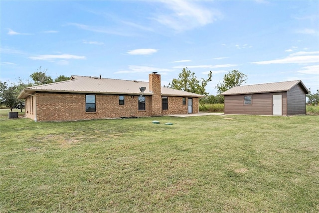 back of house featuring an outbuilding, a yard, and central air condition unit