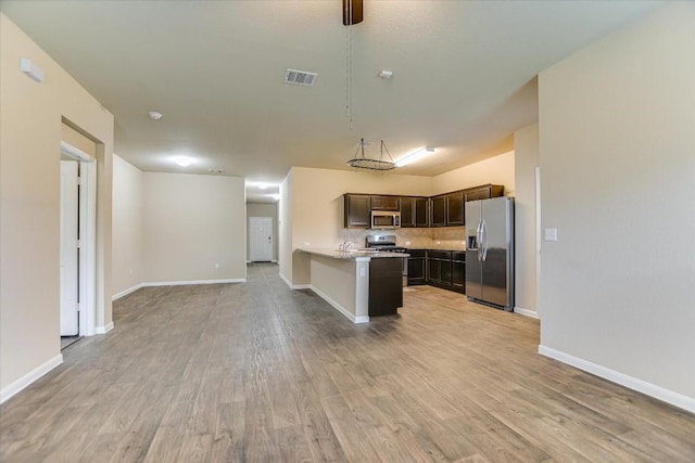 kitchen featuring backsplash, appliances with stainless steel finishes, dark brown cabinets, and light wood-type flooring