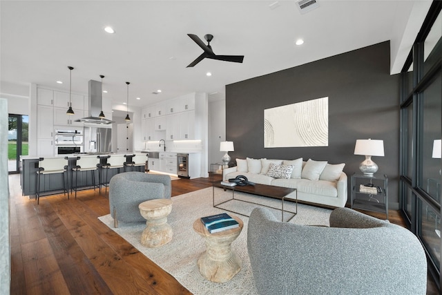 living room with dark hardwood / wood-style floors, sink, wine cooler, and ceiling fan