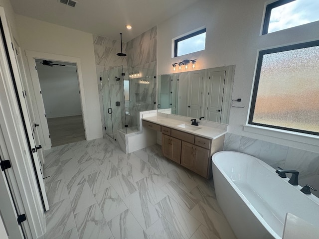 bathroom featuring vanity, tile walls, independent shower and bath, and a healthy amount of sunlight