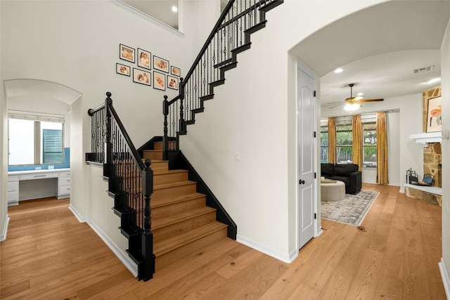 17408 Wildrye Dr, Austin, TX 78738 - stairway with arched walkways, a stone fireplace, a ceiling fan, wood finished floors, and recessed lighting