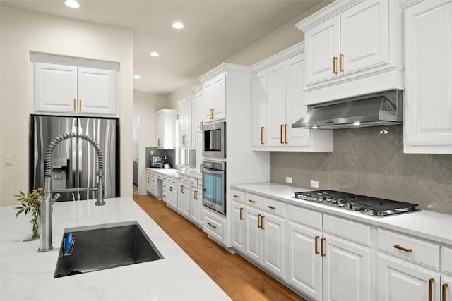 17408 Wildrye Dr, Austin, TX 78738 - kitchen featuring appliances with stainless steel finishes, light countertops, backsplash, light wood-type flooring, and white cabinets