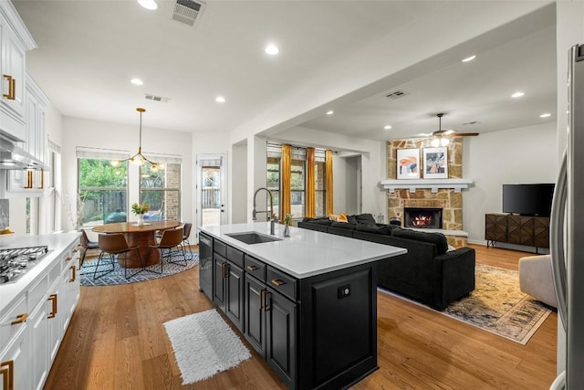 17408 Wildrye Dr, Austin, TX 78738 - kitchen with white cabinetry, dark cabinetry, ceiling fan, a stone fireplace, and light countertops