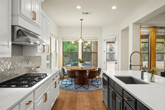 kitchen featuring stainless steel appliances, sink, pendant lighting, and white cabinets