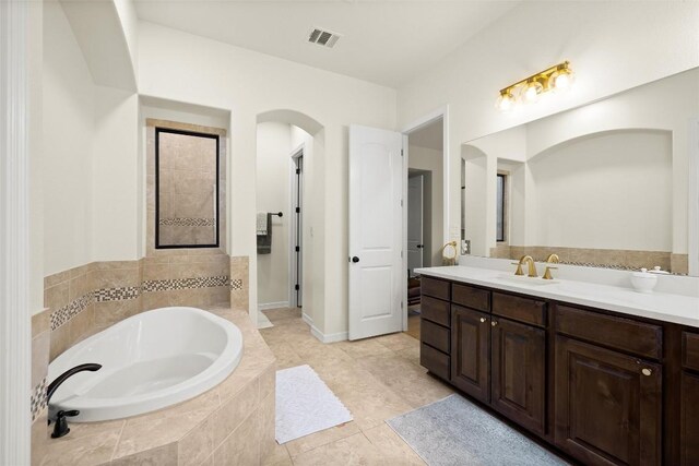 bathroom featuring vanity, tile patterned flooring, and tiled tub