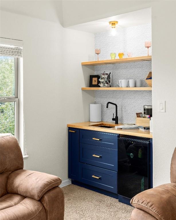 bar with tasteful backsplash, sink, black dishwasher, and blue cabinets