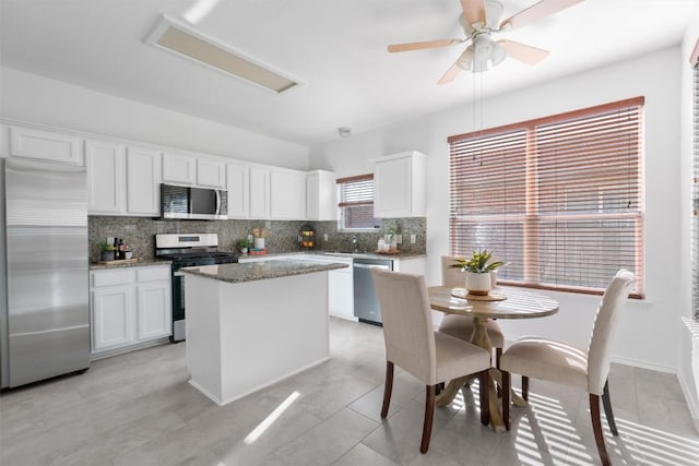 kitchen featuring white cabinetry, tasteful backsplash, a center island, dark stone counters, and stainless steel appliances