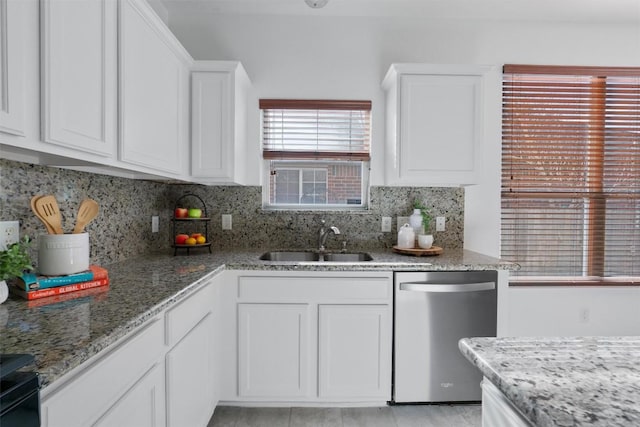 kitchen featuring sink, light stone counters, stainless steel dishwasher, white cabinets, and backsplash