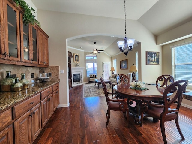 dining room with a healthy amount of sunlight, dark hardwood / wood-style floors, and vaulted ceiling