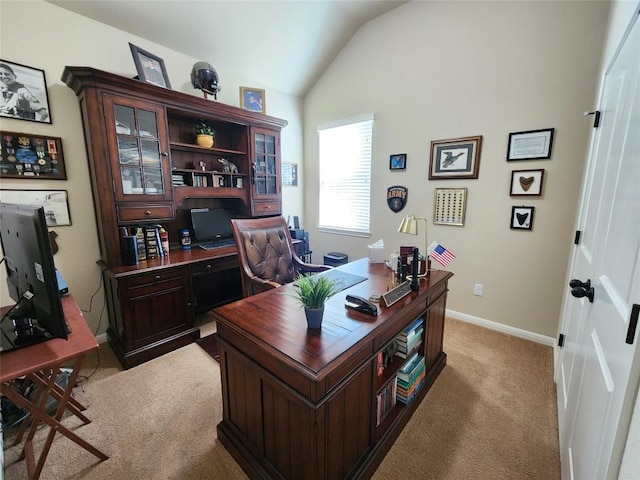 office area featuring lofted ceiling, baseboards, and light colored carpet