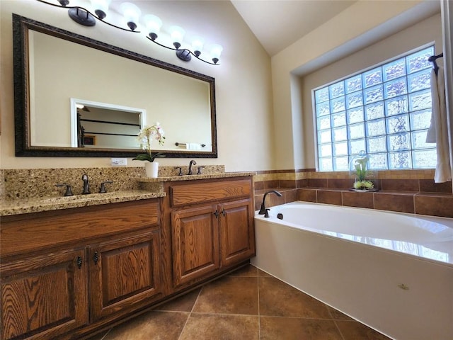 bathroom featuring tile patterned flooring, vanity, lofted ceiling, and a tub to relax in