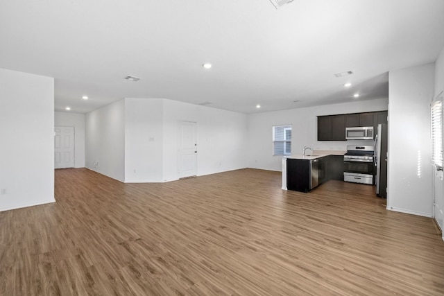 unfurnished living room with sink and light hardwood / wood-style floors