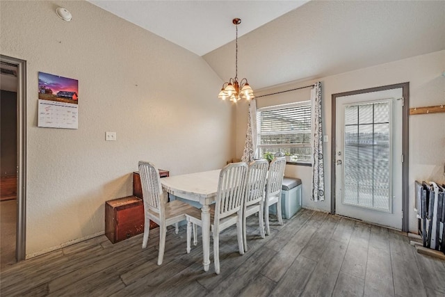 dining area with vaulted ceiling, dark wood-type flooring, and an inviting chandelier