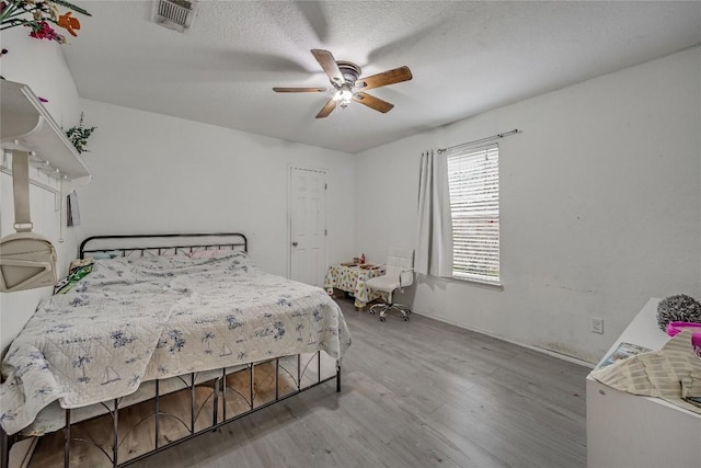 bedroom featuring ceiling fan, hardwood / wood-style floors, and a textured ceiling